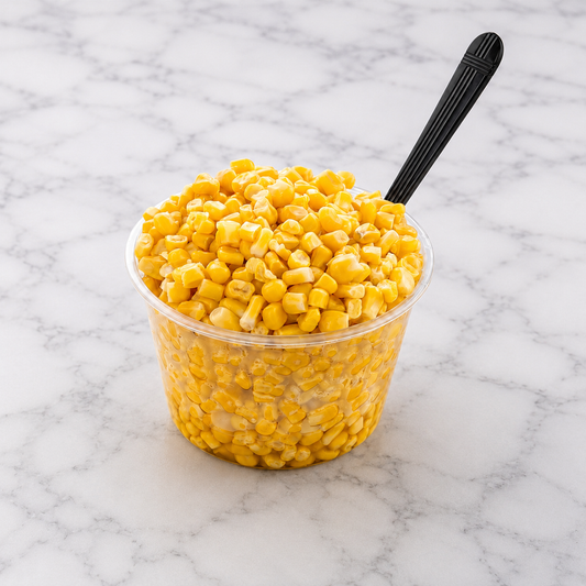 Clear container of yellow corn with a black spoon on a marble surface
