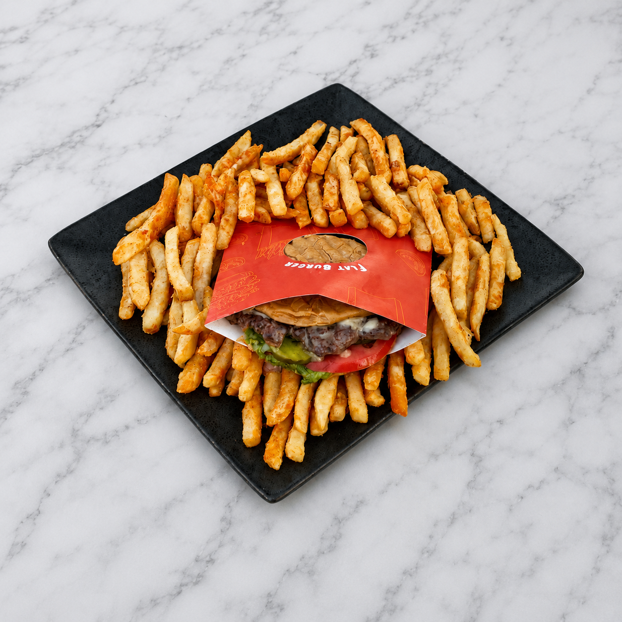 Flatburgers inside a red paper bag surrounded by crinkle-cut fries on a black plate with a marble background